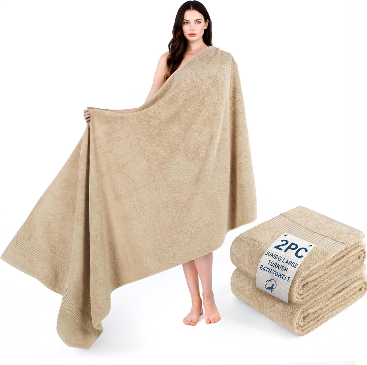 Woman holding open a large beige towel draped around her while two folded matching towels sit nearby