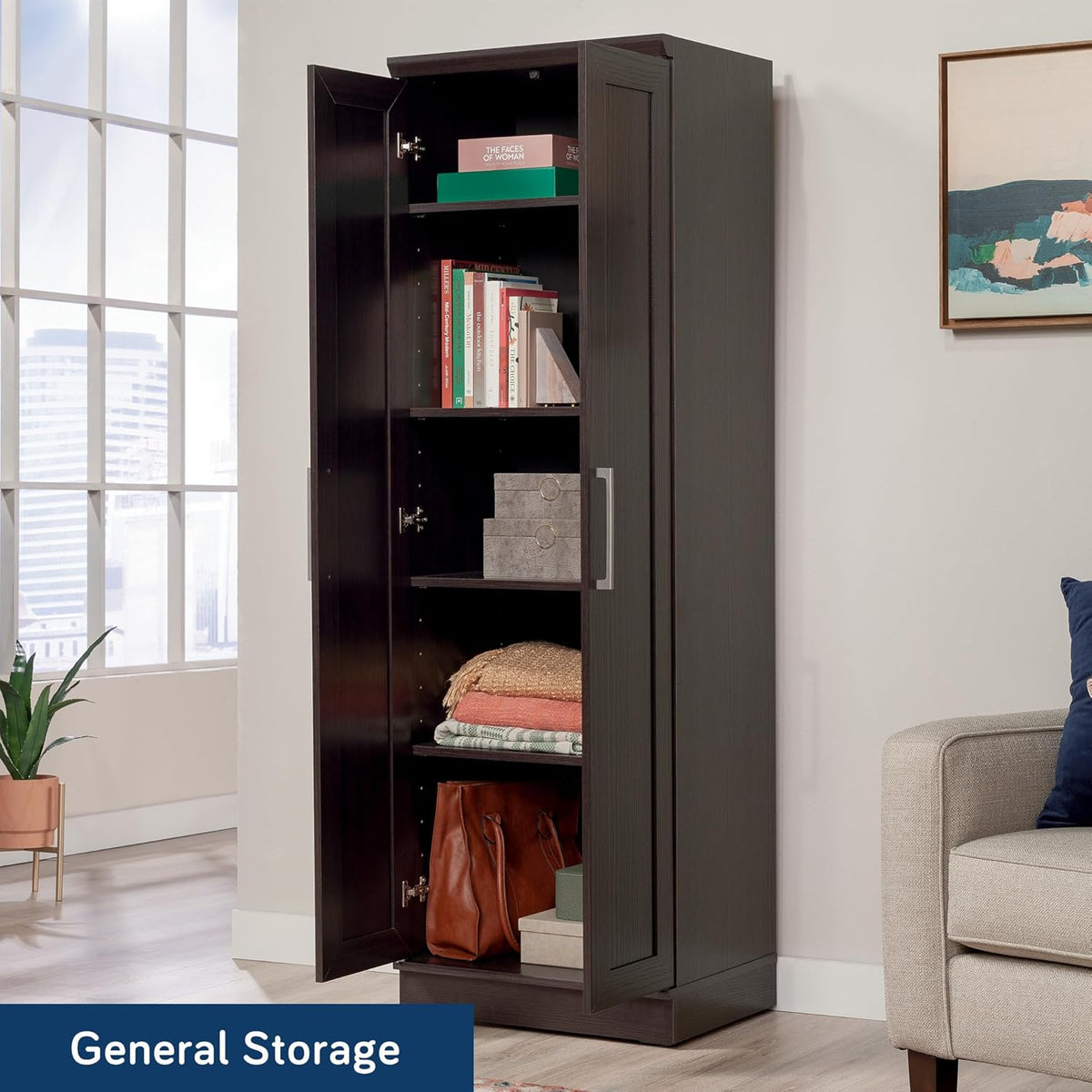 Tall dark wood storage cabinet with one door open, shelves holding books, boxes and folded linens in a living room.