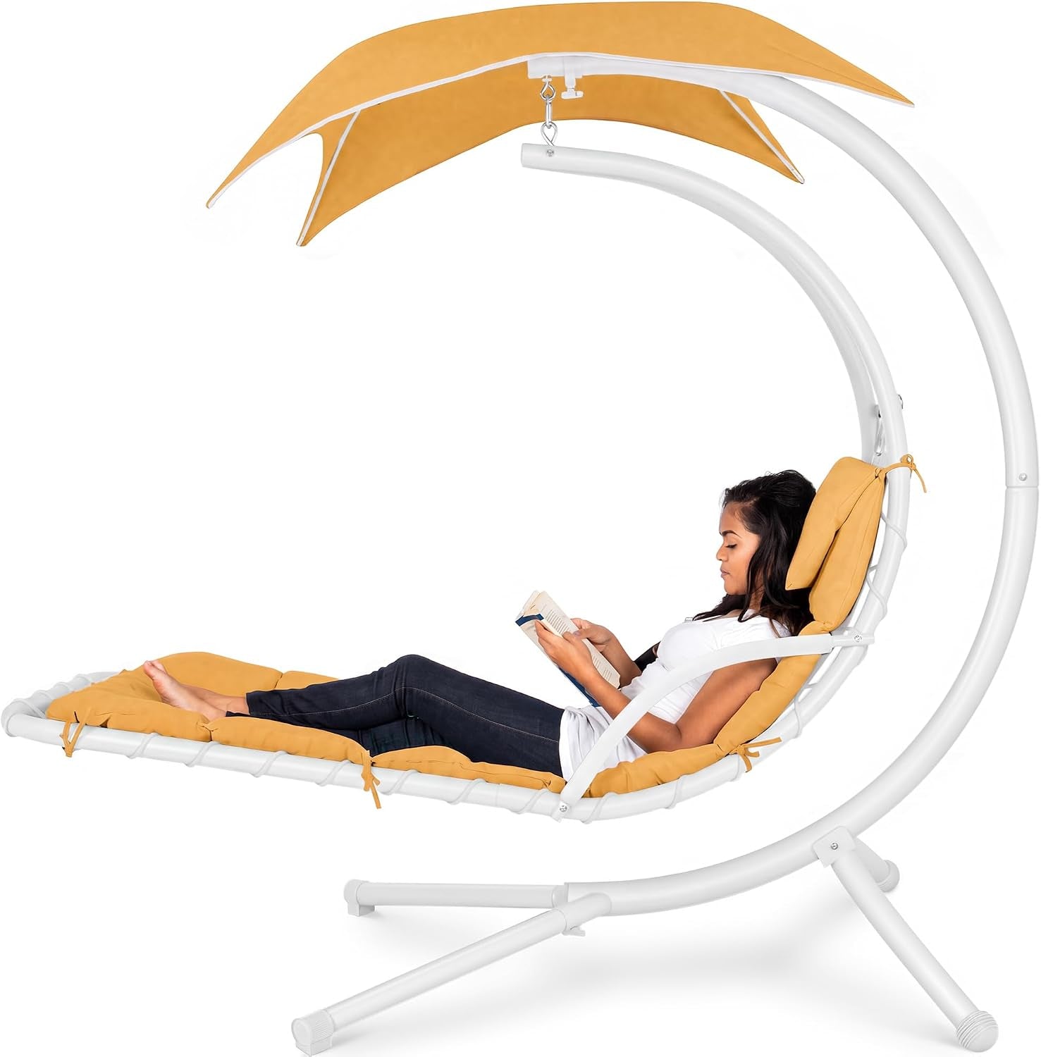 Curved hanging chaise with mustard cushions and white arched frame, a woman reclines reading under the canopy.