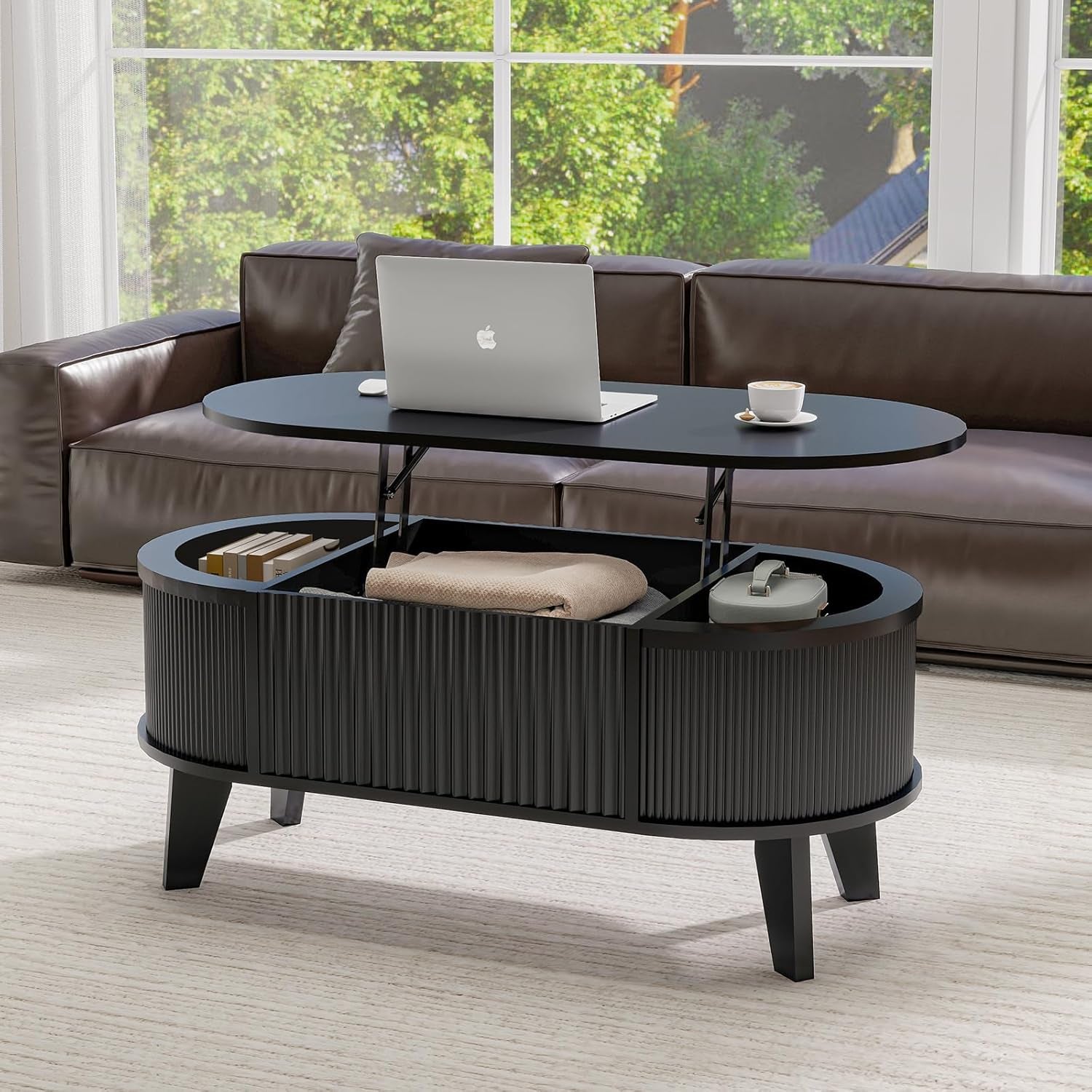 Matte black oval lift-top coffee table lifted to reveal storage bays and a folded blanket