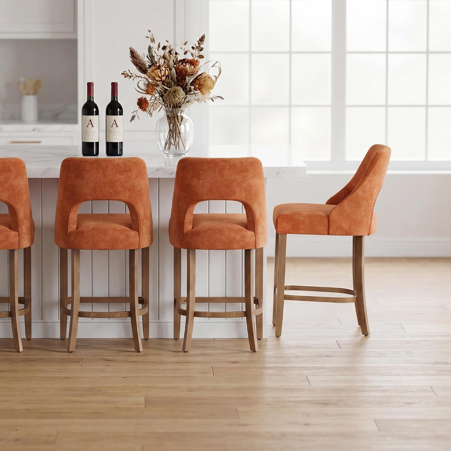 Four rust-orange upholstered counter stools lined along a white island, one stool shown in profile at the right end.