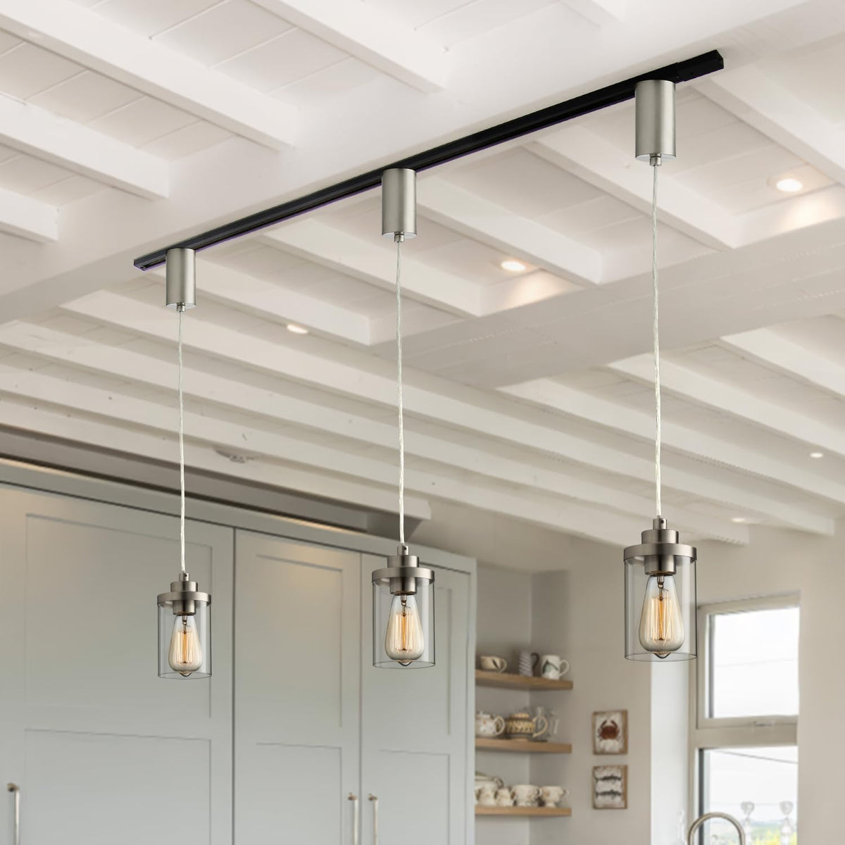 Three brushed-nickel pendants aligned on a black H-type track showing adjustable cords and clear cylindrical glass shades