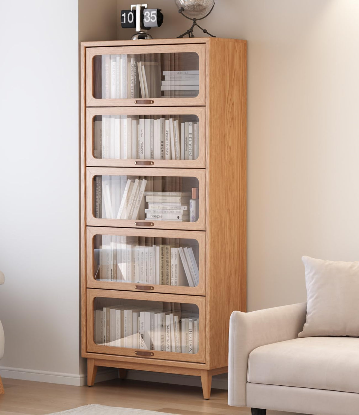 Close side view of the tall wooden bookcase with framed glass doors next to a pale sofa