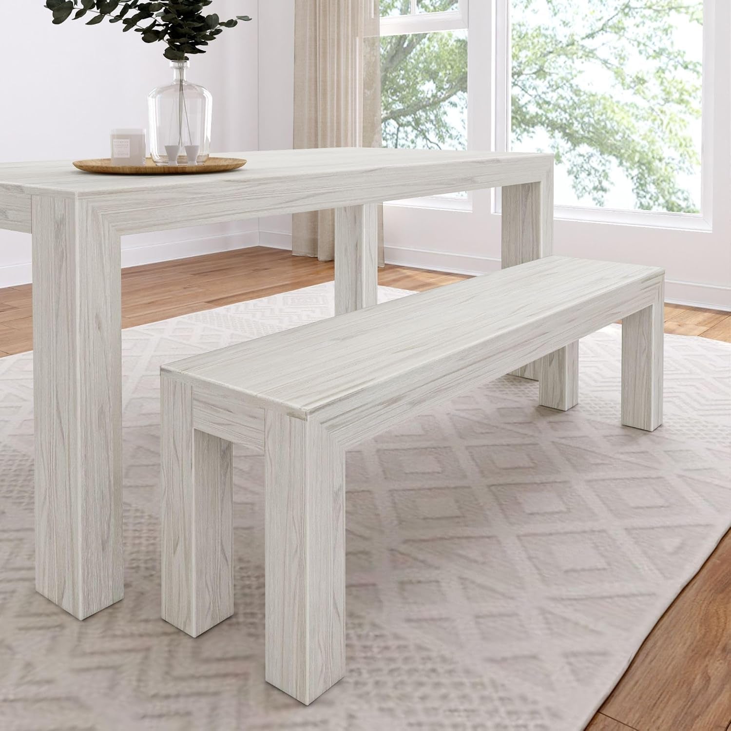 Pale whitewashed table and matching bench shown close, on a soft patterned rug