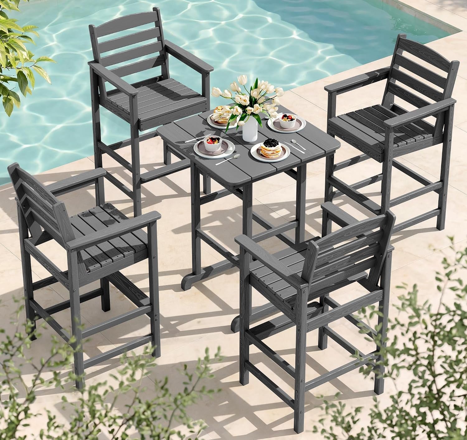 Overhead view of four dark gray bar chairs arranged around a square table set with plates by the pool.