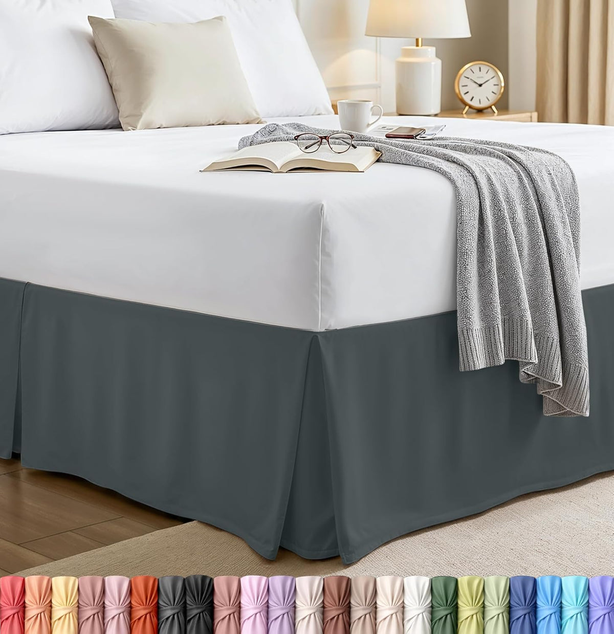 Queen bed with a deep gray pleated bed skirt, white bedding and a draped knit throw