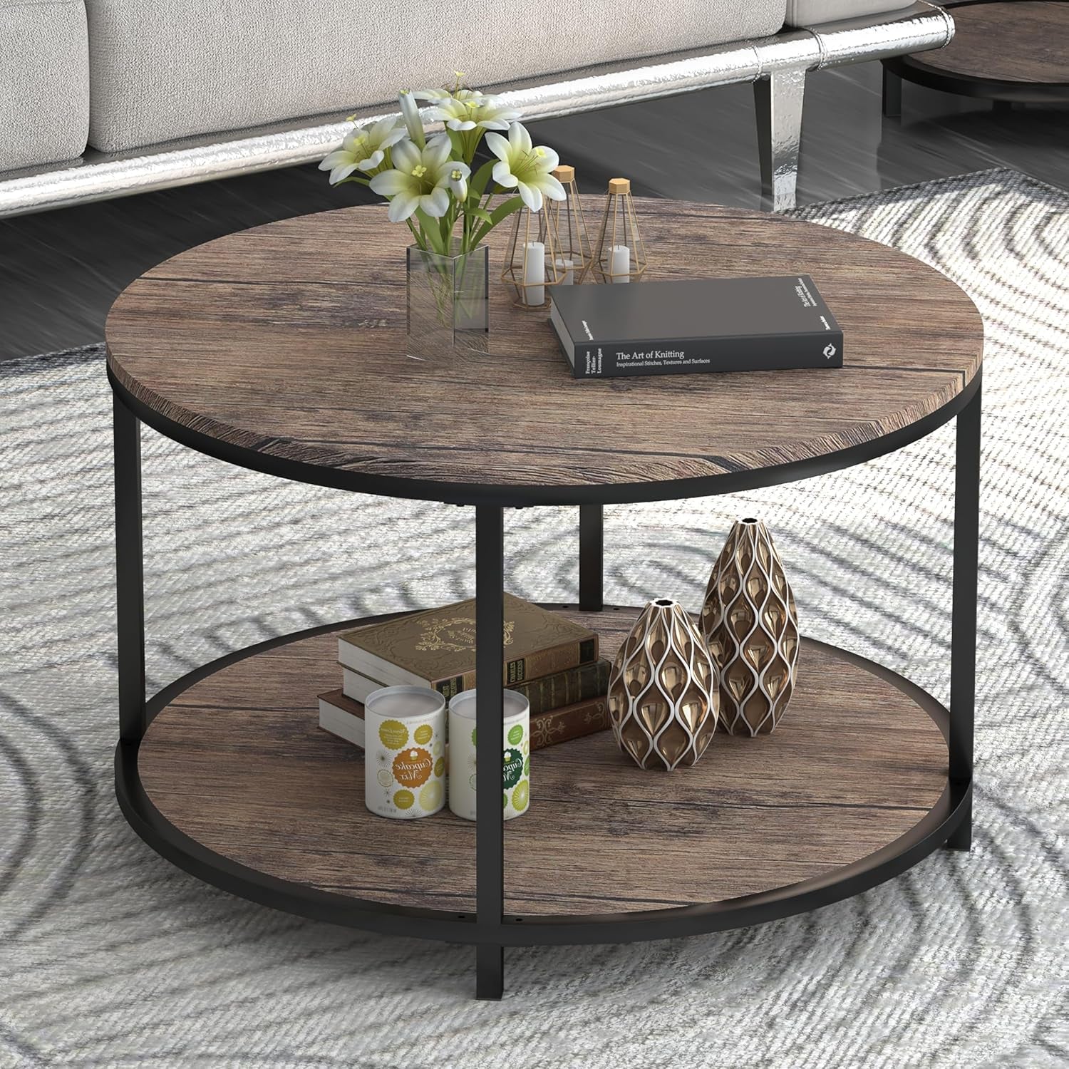 Round two-tier coffee table with light walnut wood tops and black metal frame, staged with books and vases