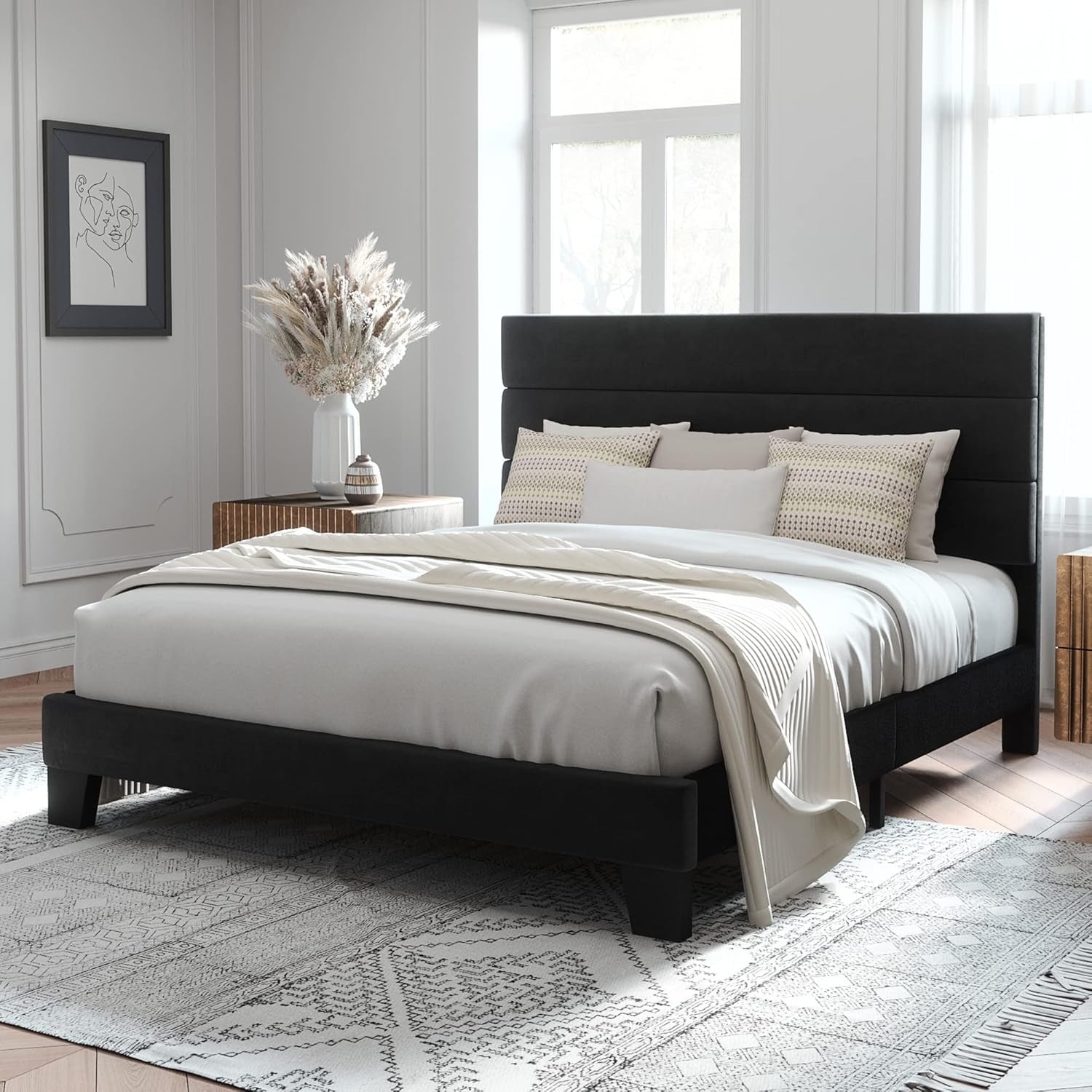 Three-quarter view of a black upholstered bed with a three-panel headboard, side rail and footboard.
