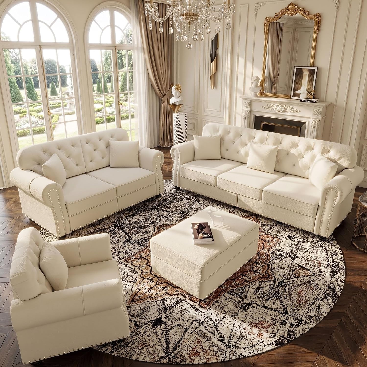 Wide-angle parlor scene with sofa, loveseat and ottoman under a crystal chandelier, arched windows and ornate fireplace.