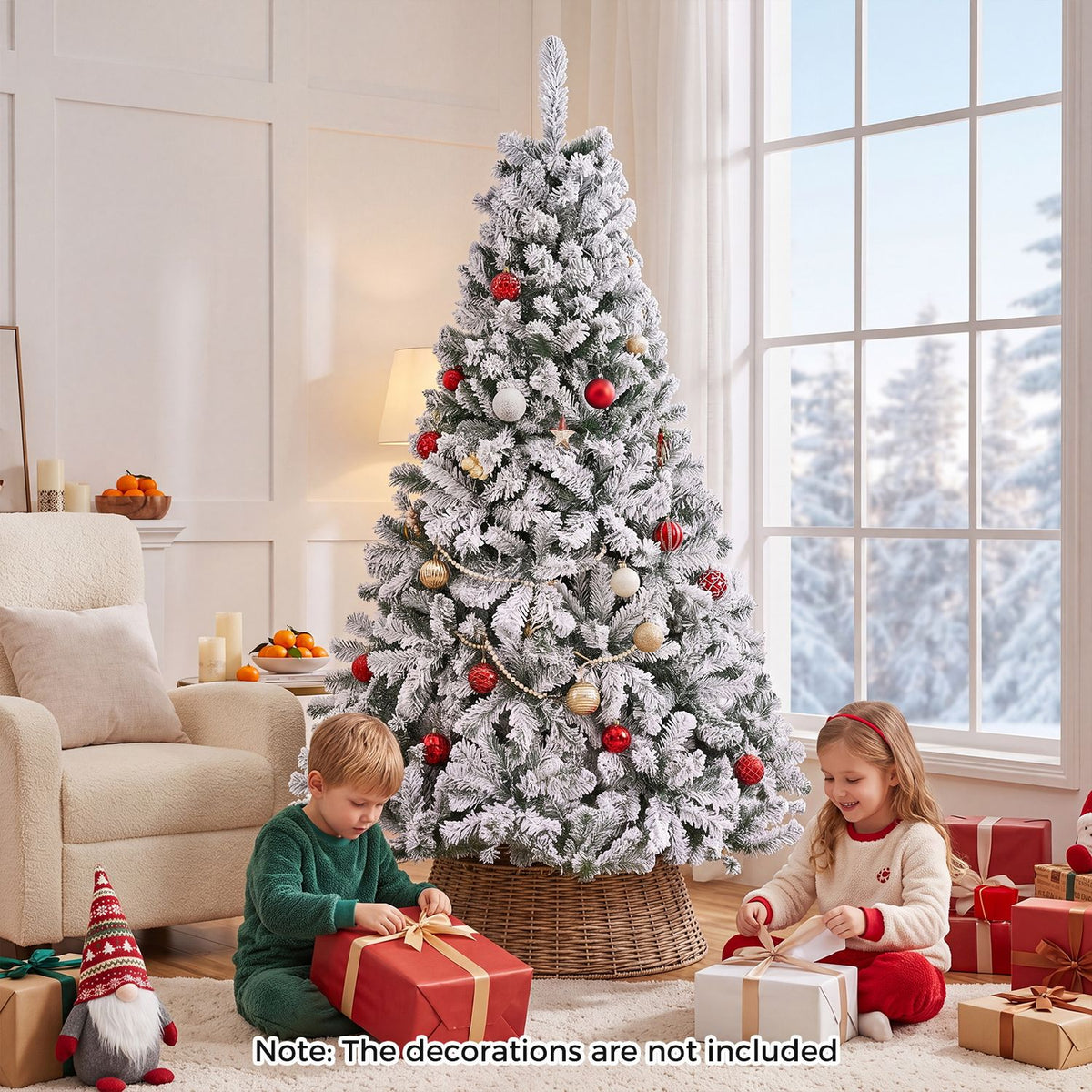 Snow-flocked tree decorated with red and gold ornaments as children wrap presents nearby.