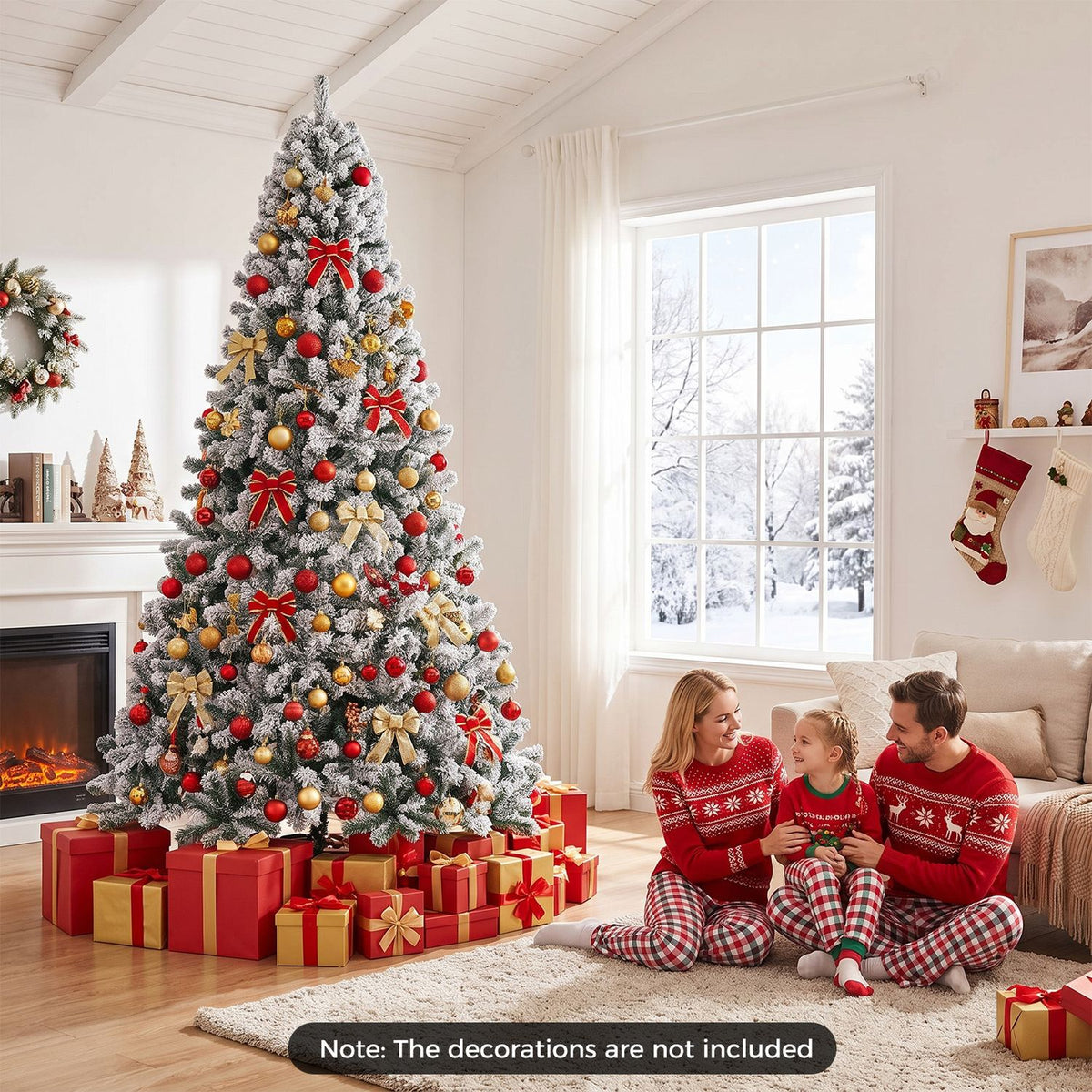 Decorated flocked Christmas tree beside a family sitting together on the floor in a bright living room.