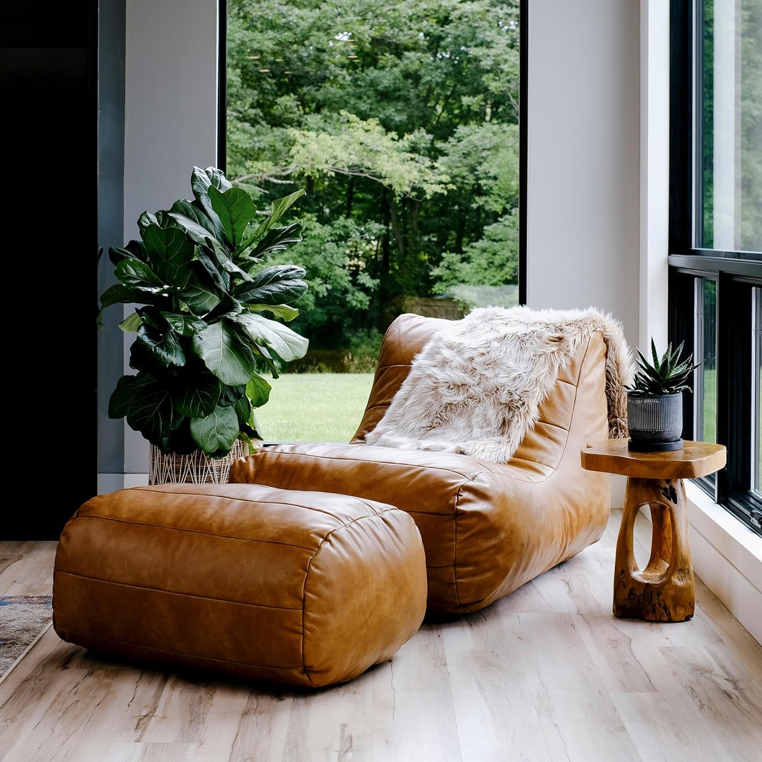Copper-toned leather-look lounger with matching ottoman by a large window, faux fur throw over the back