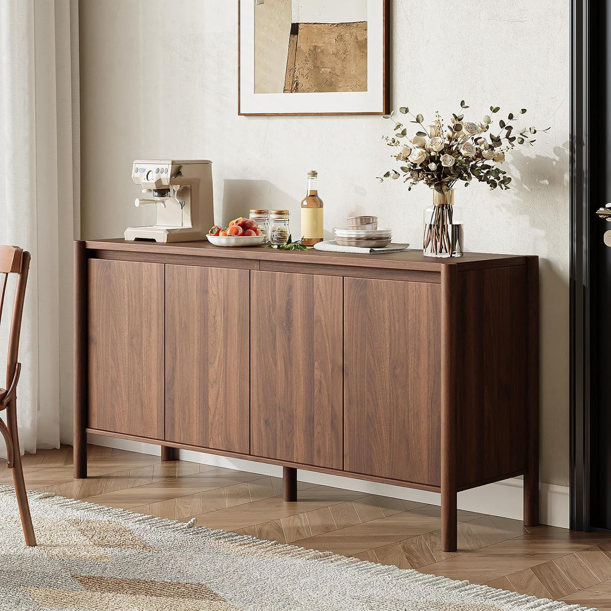 Side-angle view of the cabinet in a dining vignette with a coffee maker and vase of flowers on top.
