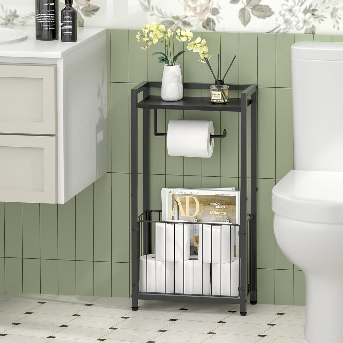 Front view of the holder's bottom wire basket storing multiple toilet rolls and magazines next to a toilet