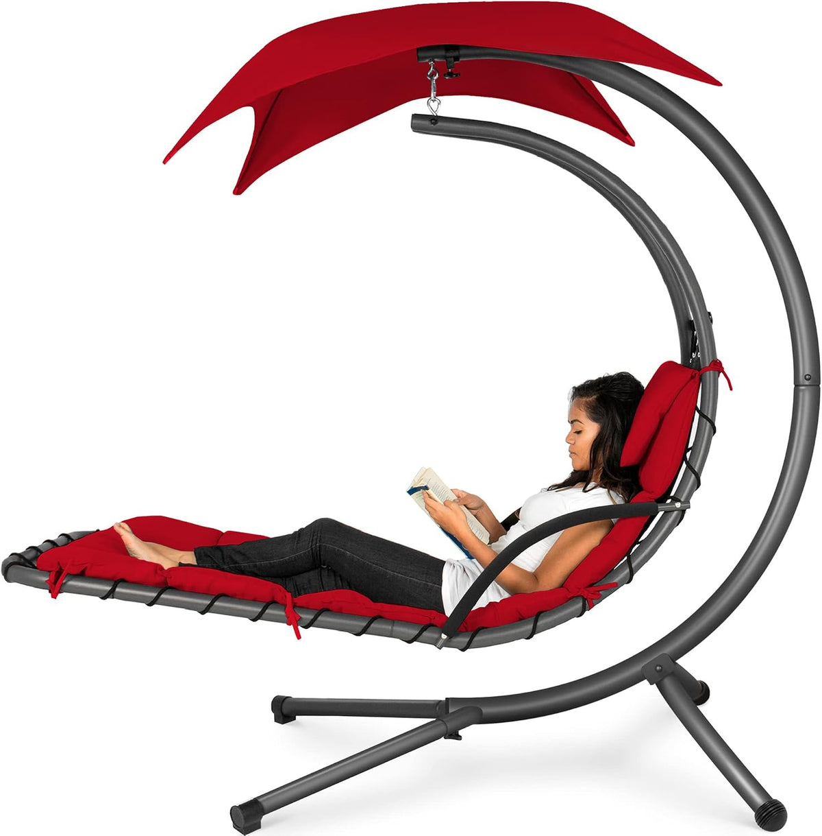 Curved hanging chaise swing in dark gray frame with red cushions and canopy, woman reading