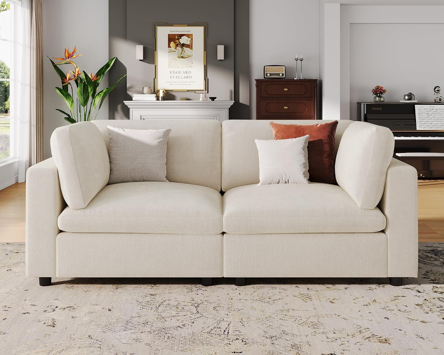 Straight-on close view of a two-seat cream sofa module with square cushions and two decorative pillows.