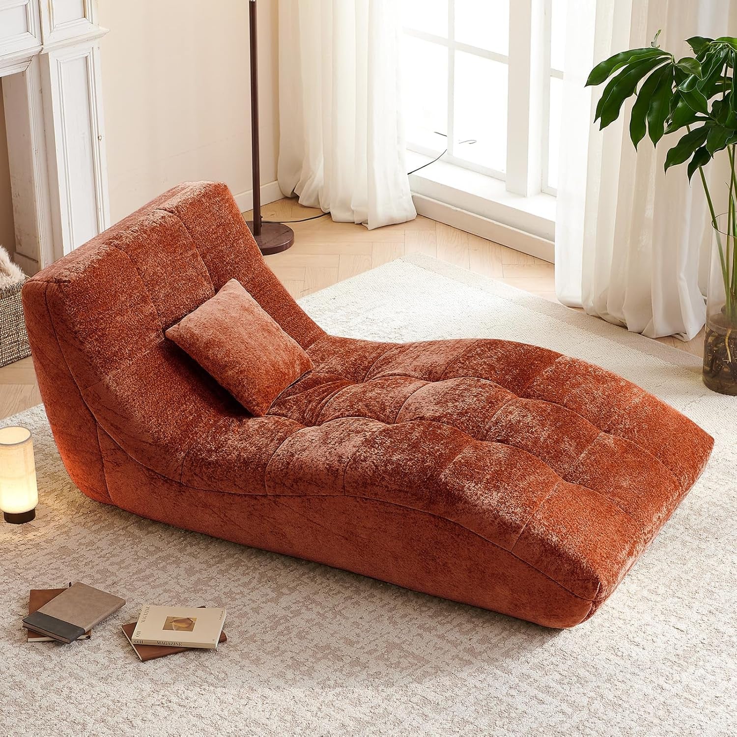 Curved tufted chaise upholstered in a deep rust-orange fabric shown angled in a light-filled room.