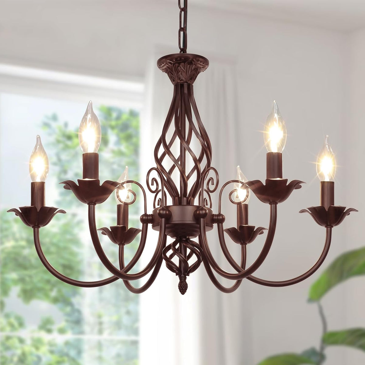 Angled close-up of a six-arm matte black candle-style chandelier hanging in a bright room.