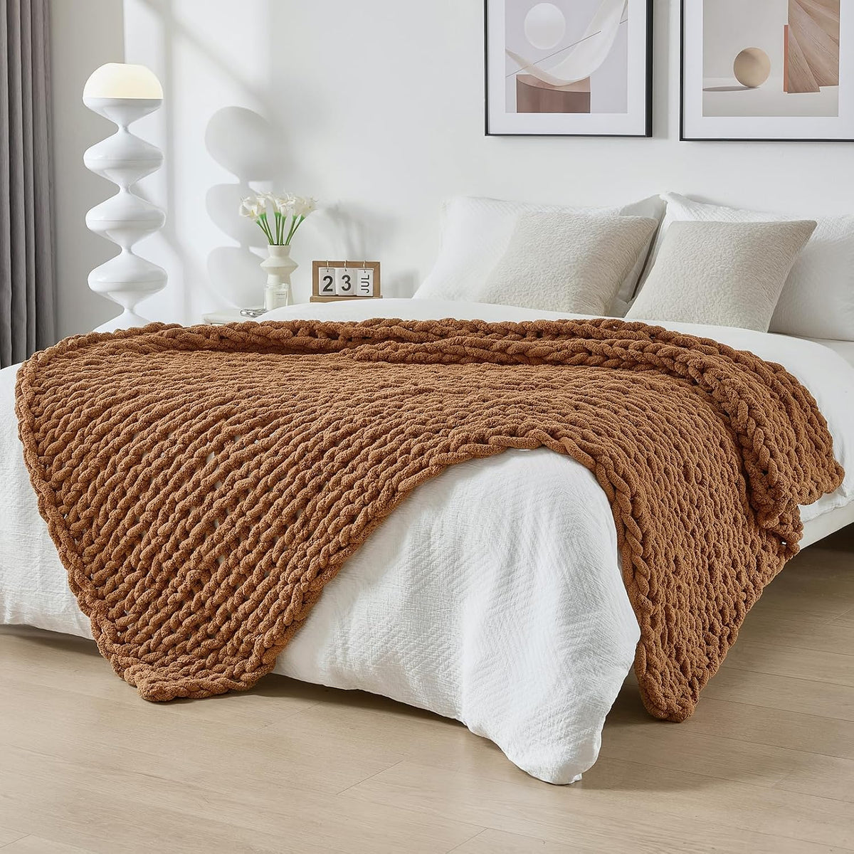 Warm brown chunky knit throw casually laid across a white bedspread in a softly styled bedroom.