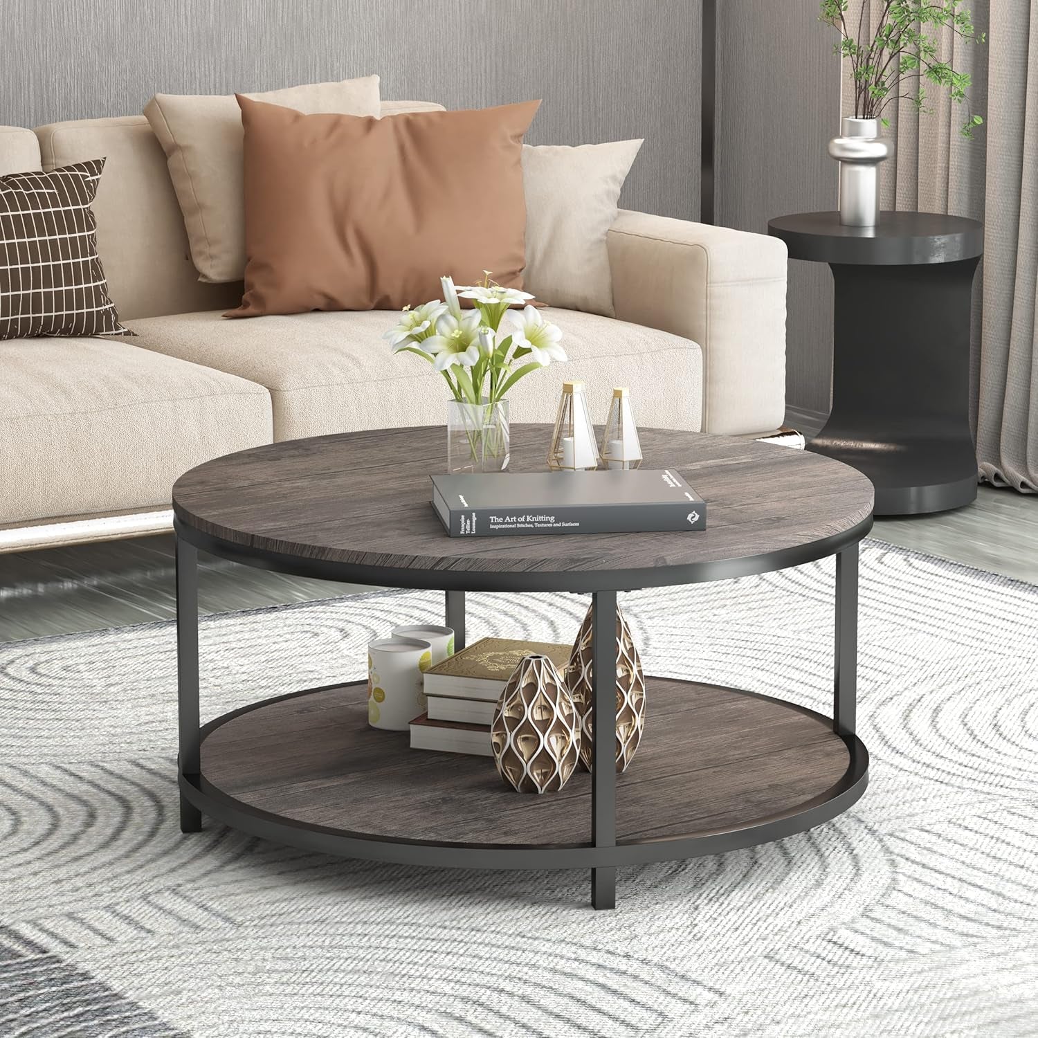 Round coffee table in a living room setting with sofa behind and decorative items on top