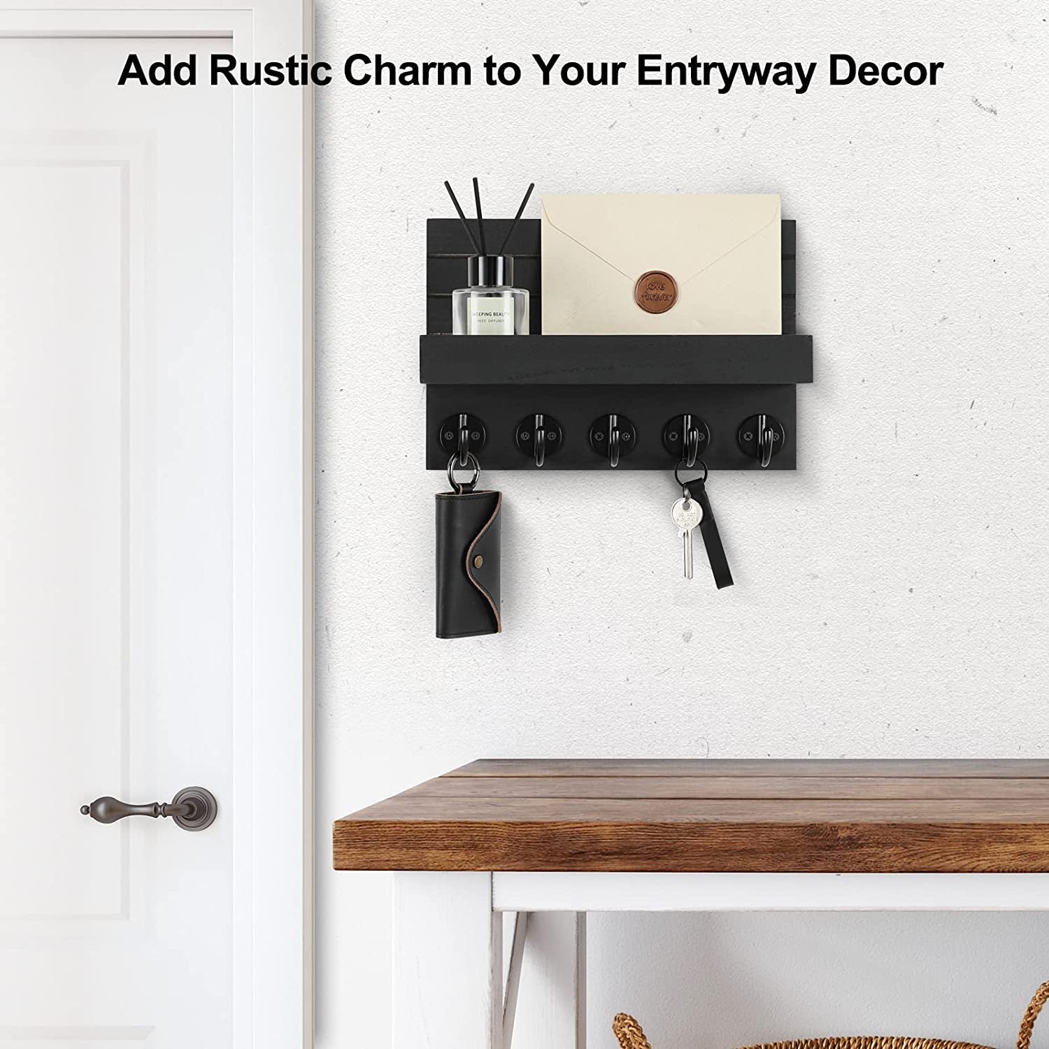 Black key holder mounted by a doorway, with an envelope and diffuser on the shelf and keys below.