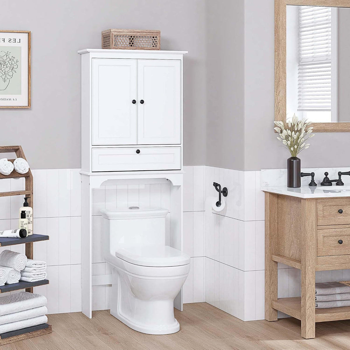 White over-the-toilet cabinet installed above a toilet with recessed panel doors and black knobs, styled in a bathroom