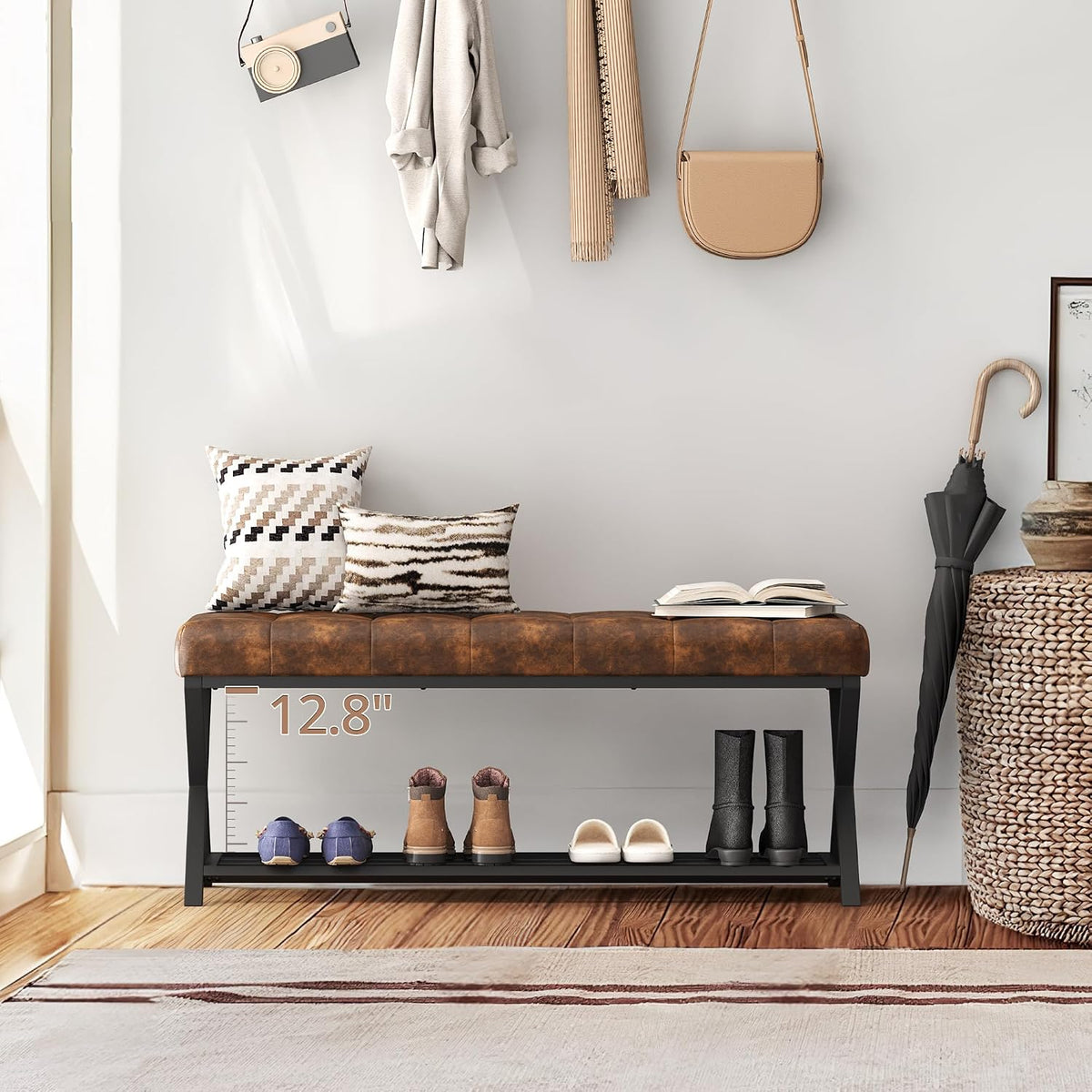 Brown tufted bench in entryway with pillows, umbrella and shoes on the lower shelf, straight-on view