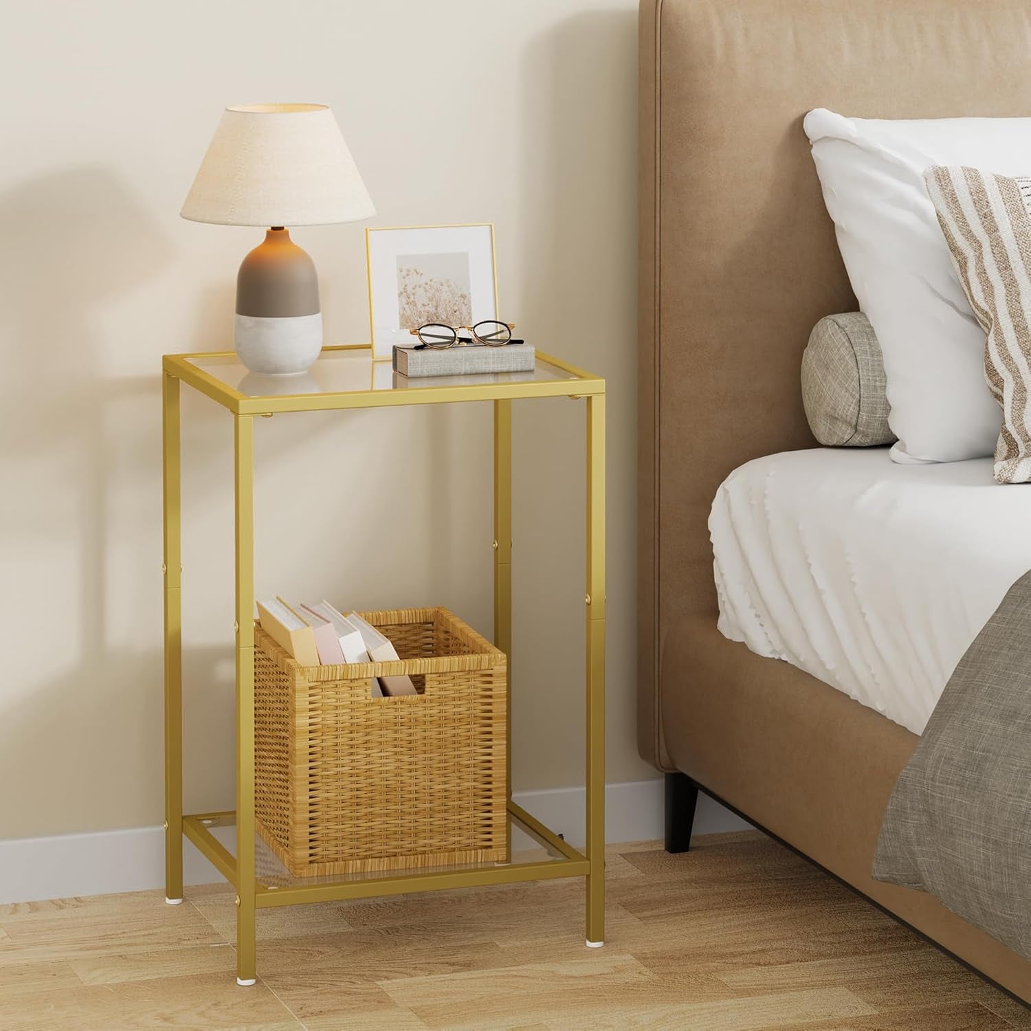 Gold side table used as a bedside table holding a lamp and a woven storage basket on lower shelf