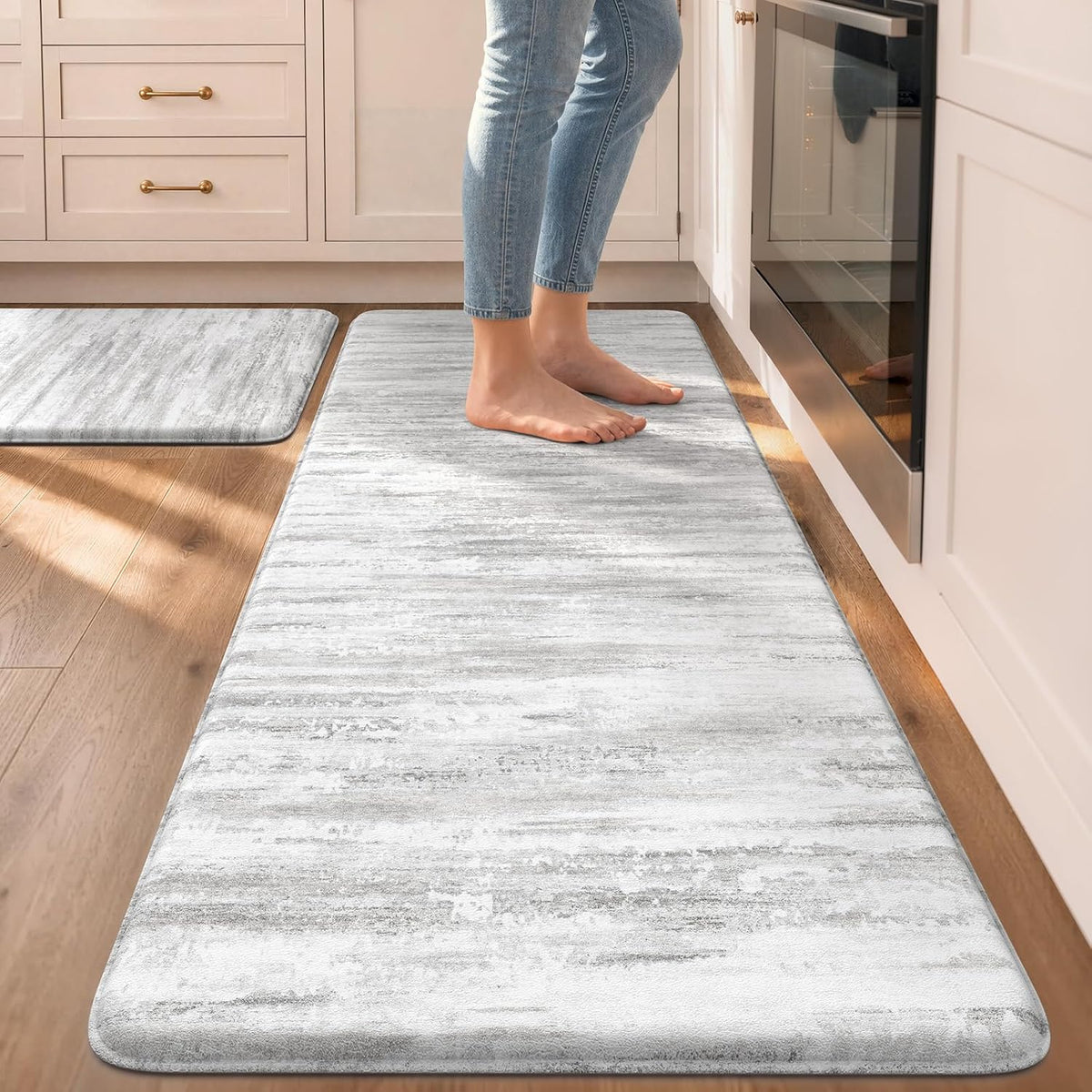 Long light-gray marbled runner on wood floor with bare feet standing near an oven, small matching mat visible in background.