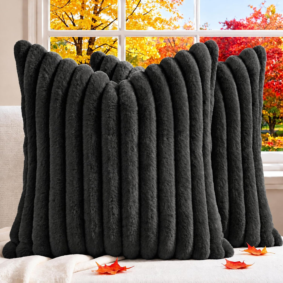 Front view of a dark charcoal ribbed faux-fur pillow cover propped on a sofa with scattered autumn leaves.