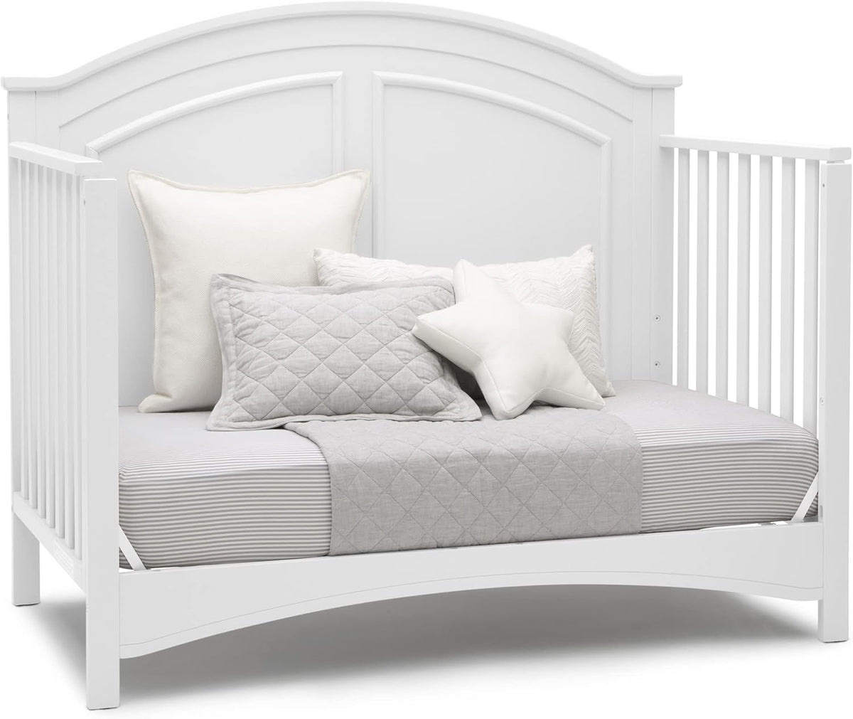 White daybed setup with striped mattress, gray quilt and assorted pillows against arched headboard