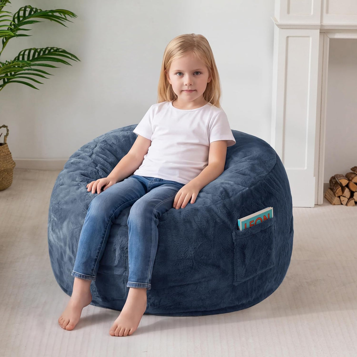Young girl seated on a navy blue bean bag, side pocket holding a book visible.