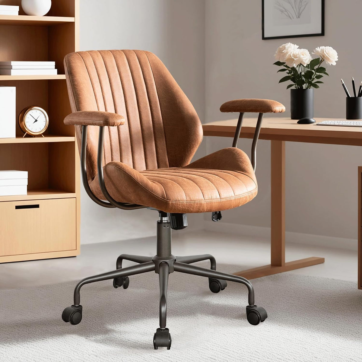 Warm brown faux-suede chair, three-quarter front view beside a wood desk and low bookshelf