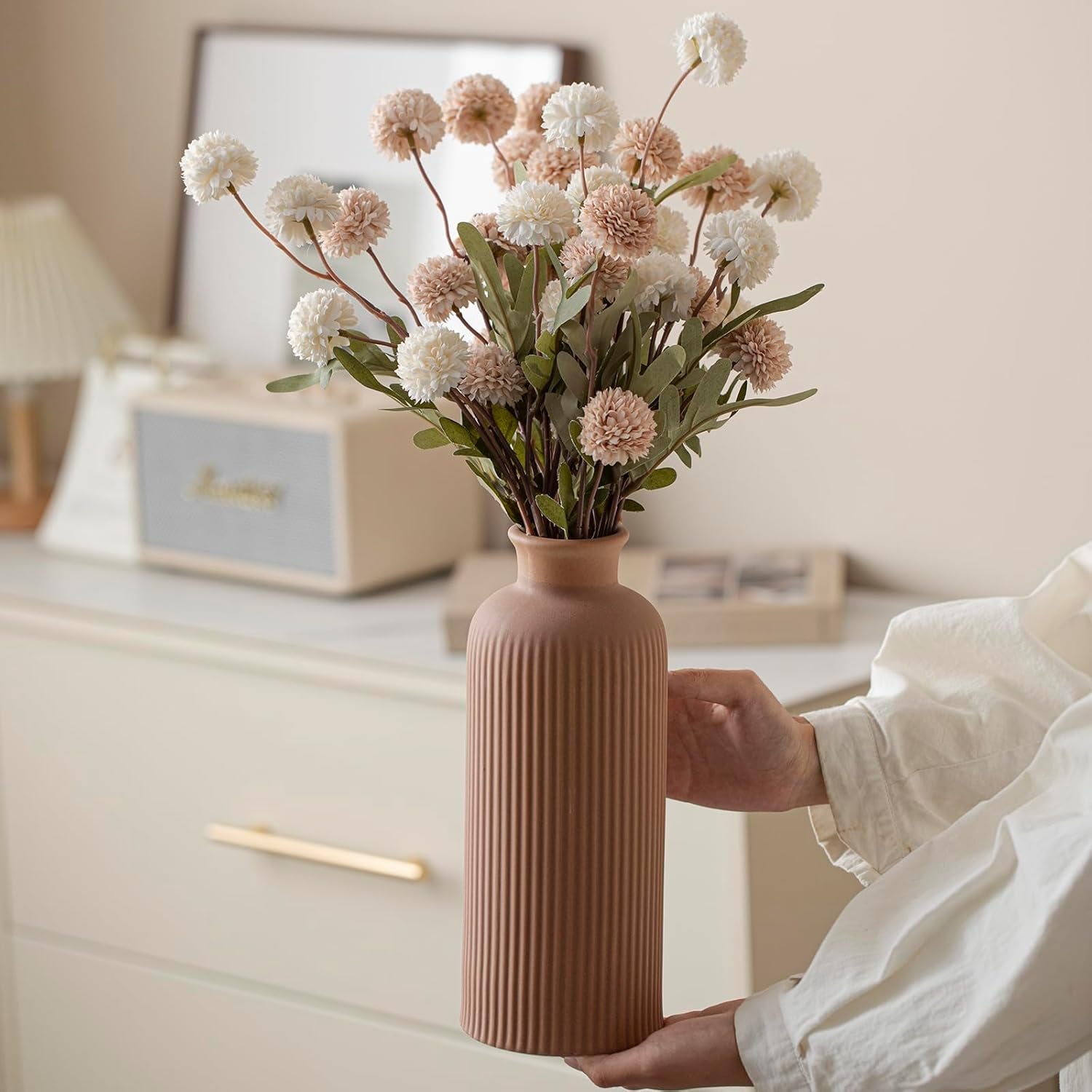 Tall matte brown ribbed bottle-shaped vase held by hands, showing full height and vertical ridged texture.
