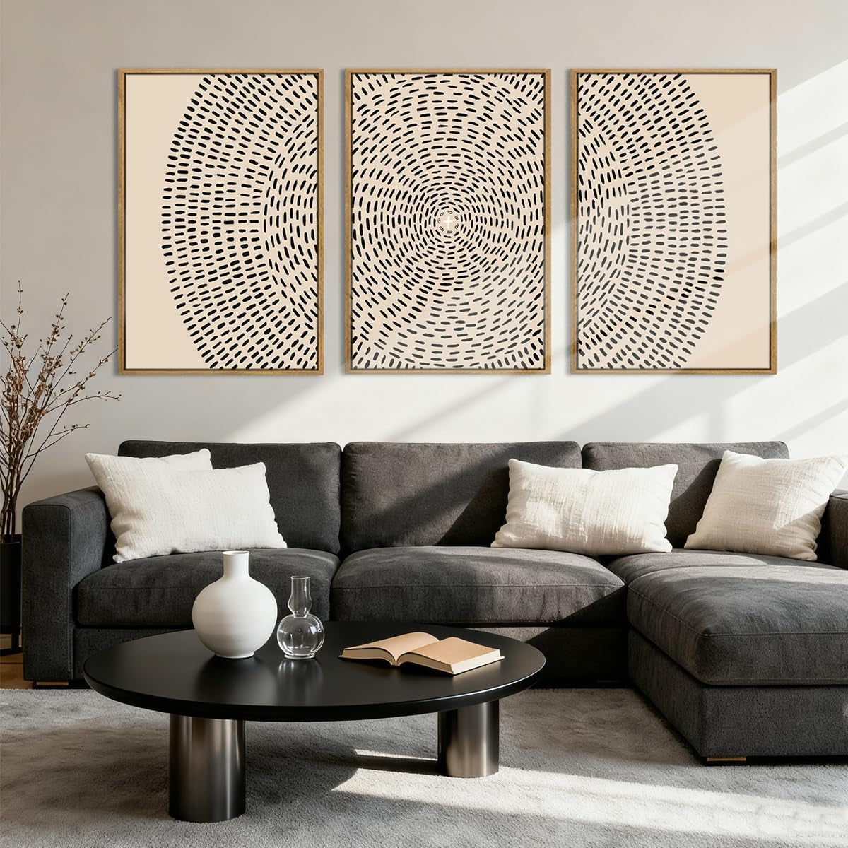 Three framed circular-pattern prints arranged above a dark gray sectional sofa with a round black coffee table.
