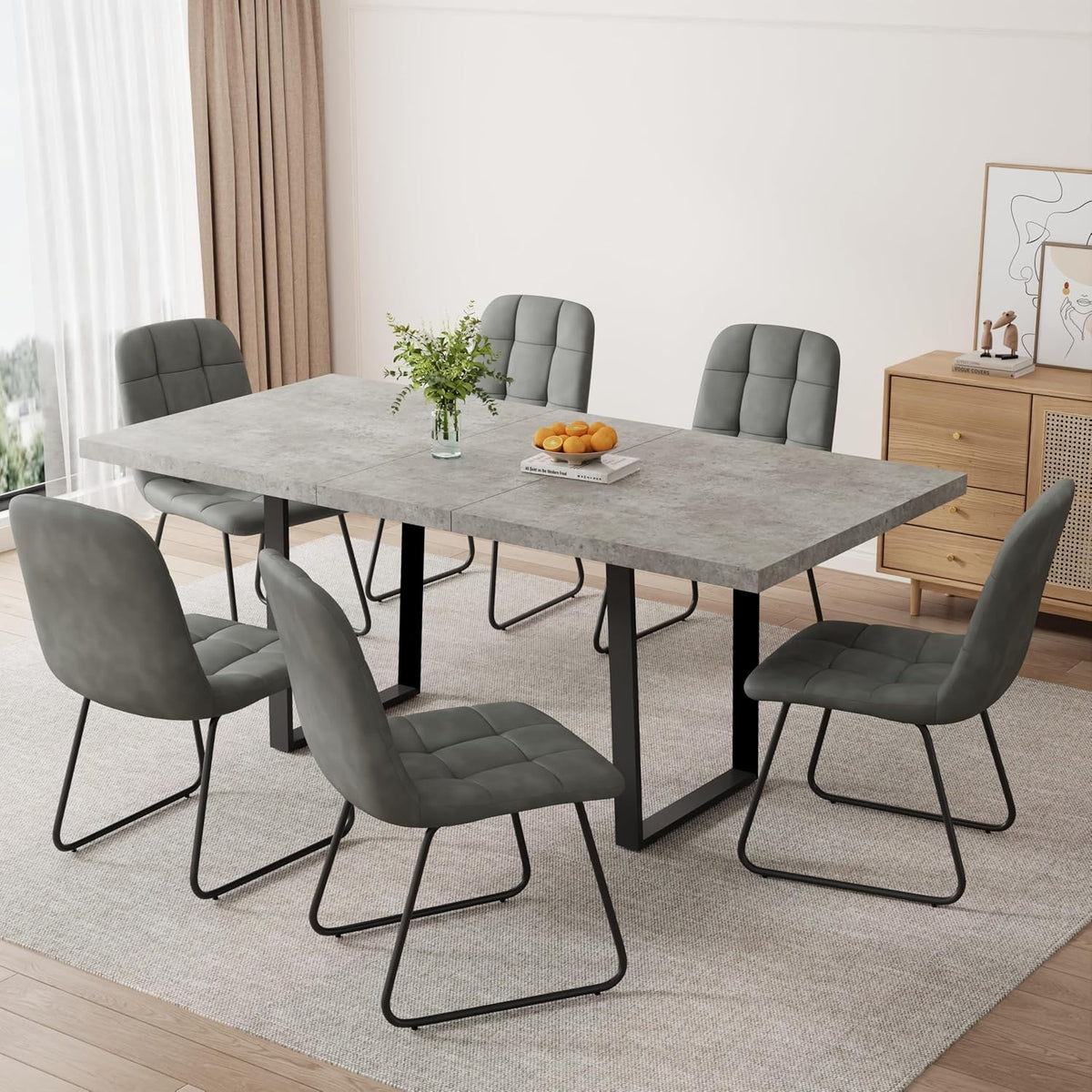 Room view highlighting quilted gray chairs with sled-style metal bases around a concrete-look table on a rug.