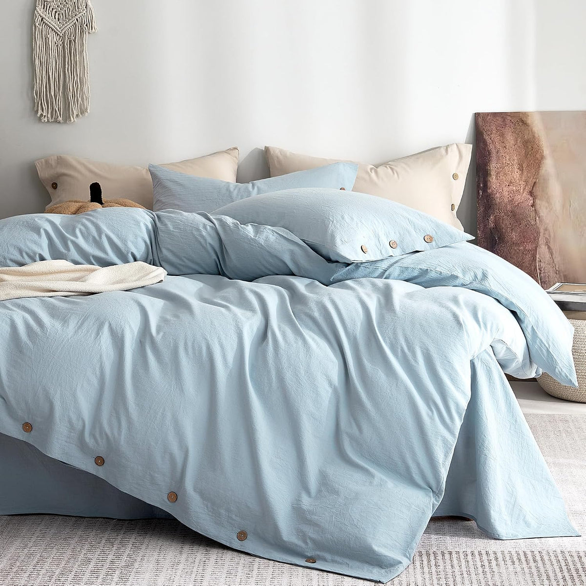 Light blue duvet and pillow set on a bed with wooden buttons along the bottom edge.