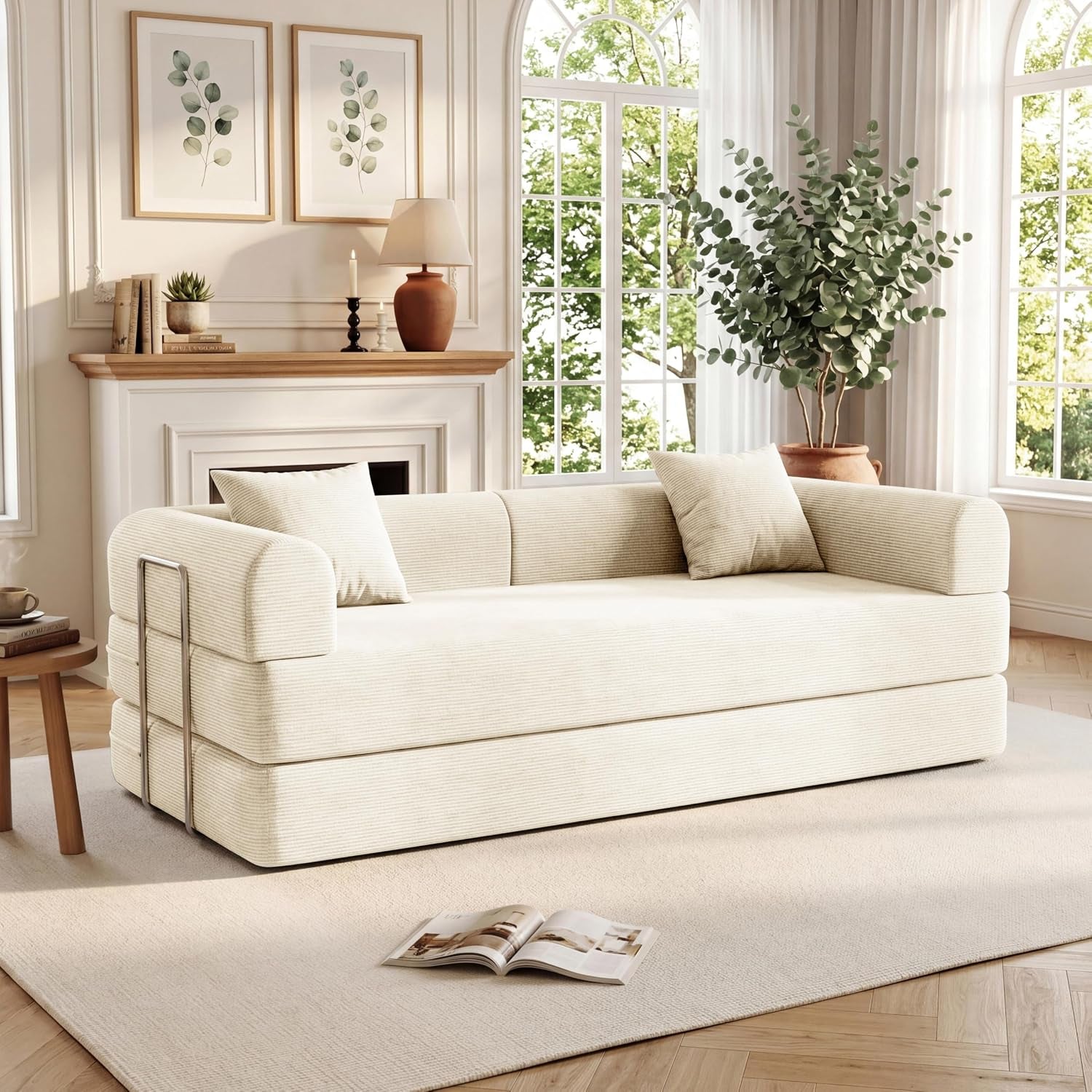 Ivory corduroy sofa placed in front of tall windows with leafy plants and decorative mantel behind it.