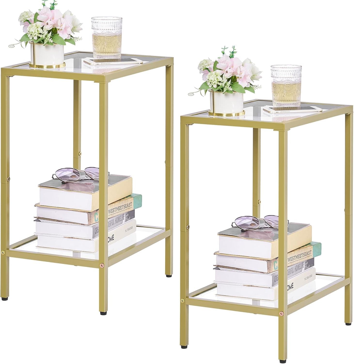 Pair of gold metal and glass side tables shown side by side with stacked books, sunglasses and small vases