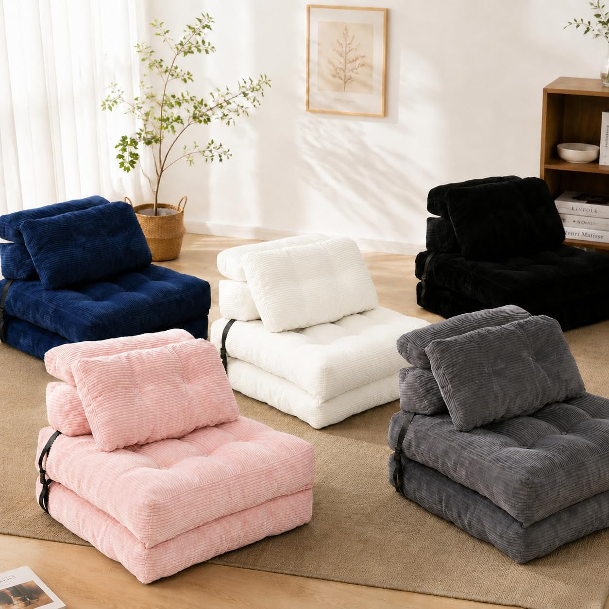 Five corduroy folding floor chairs in navy, pink, white, black, and gray arranged on a rug in a bright room.