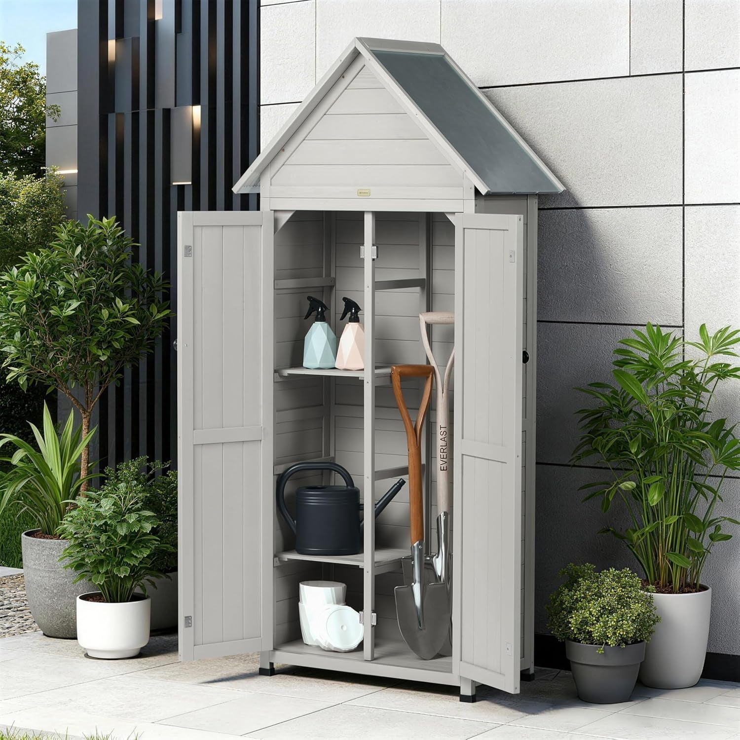 Gray vertical outdoor storage cabinet with pitched roof on a patio beside potted plants, doors open to reveal shelves and a t