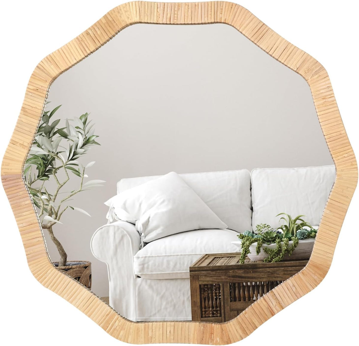 Scalloped/decagonal rattan-framed mirror reflecting a white sofa, wooden coffee table and nearby plants.