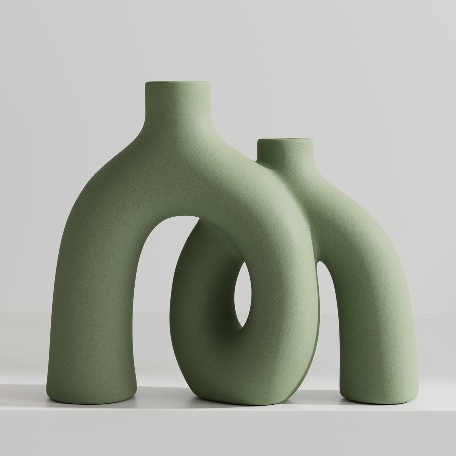 Pair of sculptural donut vases in a soft matte green displayed side by side