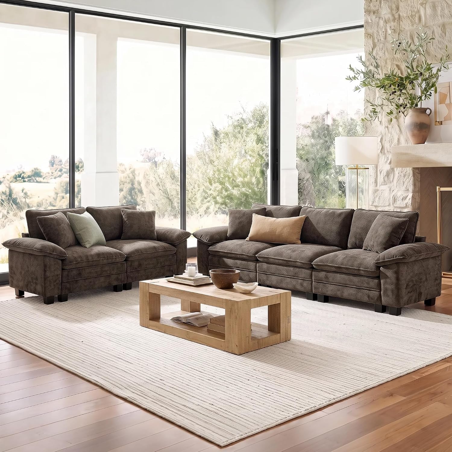 Sunlit living room with a dark brown three-seat sofa and matching loveseat flanking a low wooden coffee table.