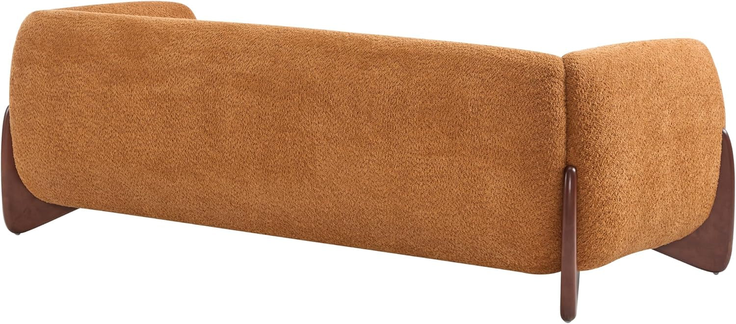 Rear view of a caramel-brown boucle sofa showing rounded back and wooden leg accents.