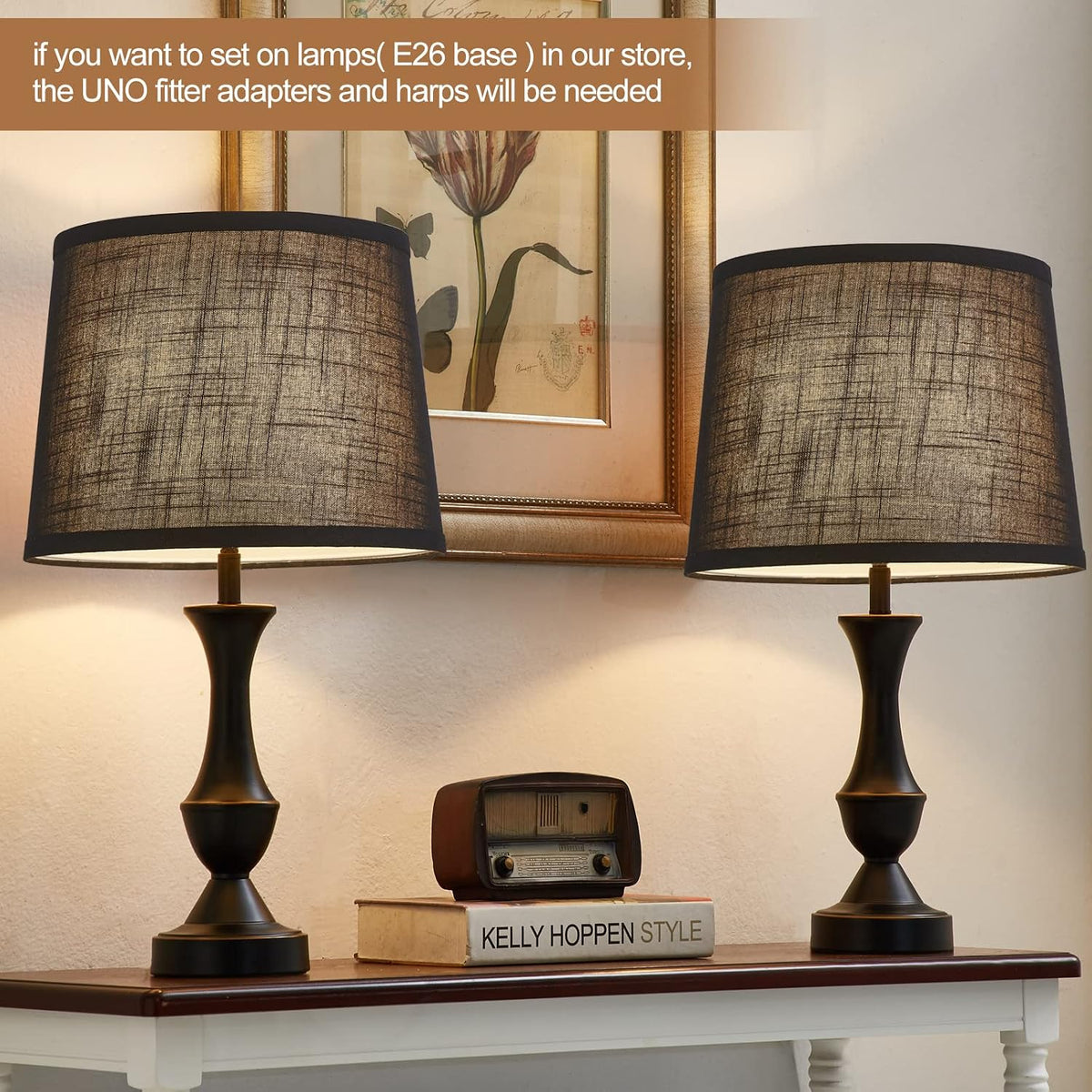 Pair of black linen shades installed on table lamps, lit to show warm filtered light on a console table