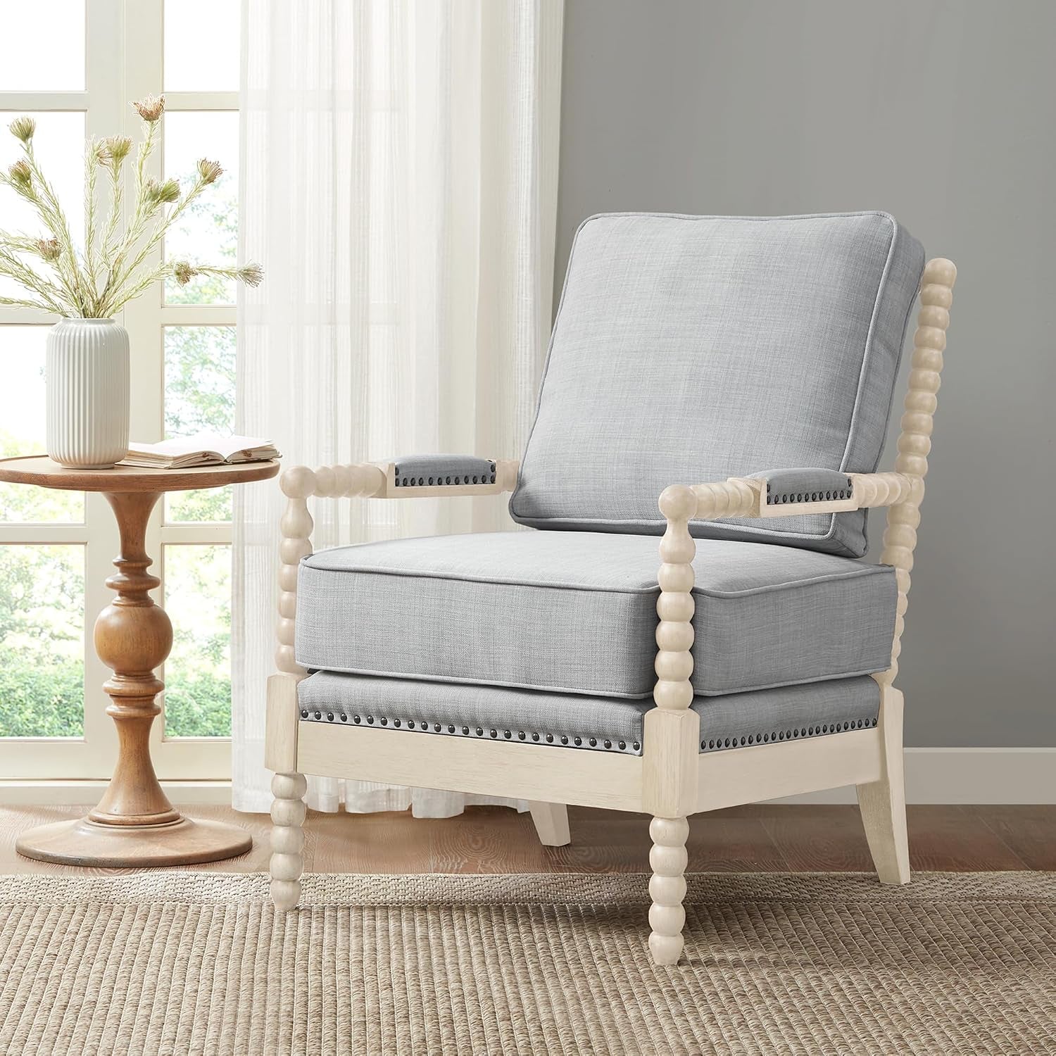 Light blue upholstered bobbin-leg accent chair front-right angled view in a sunlit room