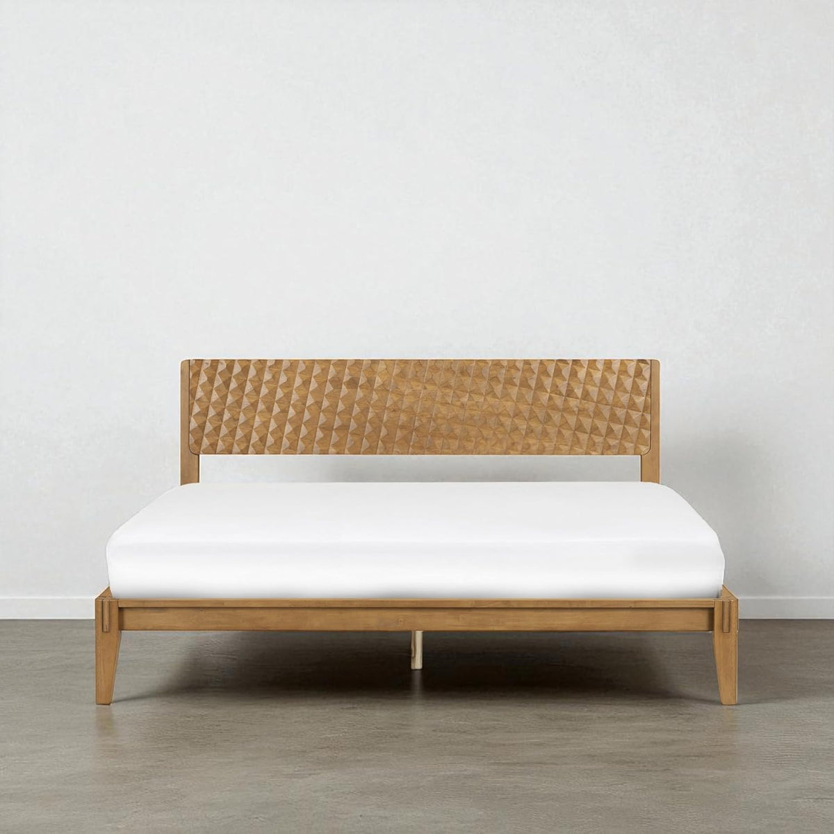 Front view of the bed in a light natural wood finish with carved geometric headboard