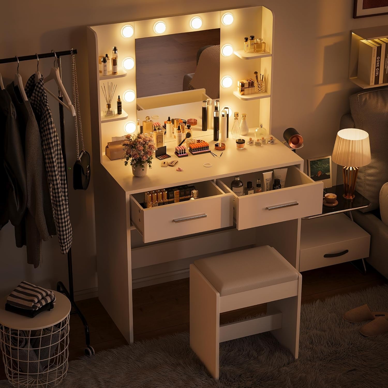 Evening scene of the illuminated vanity showing two drawers pulled out and a padded stool tucked underneath