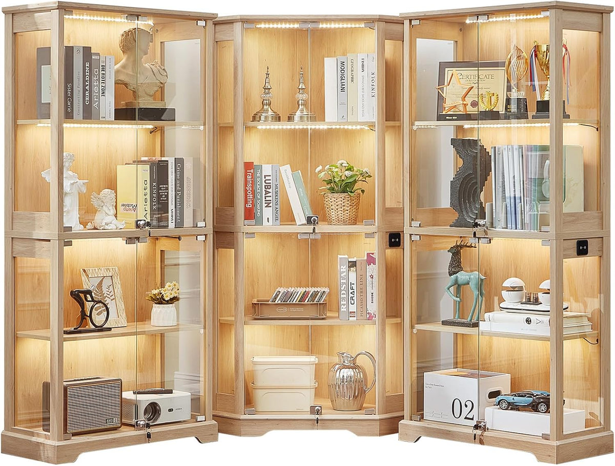 Three natural wood finish glass display cabinets arranged together, each illuminated and staged with books and decor.